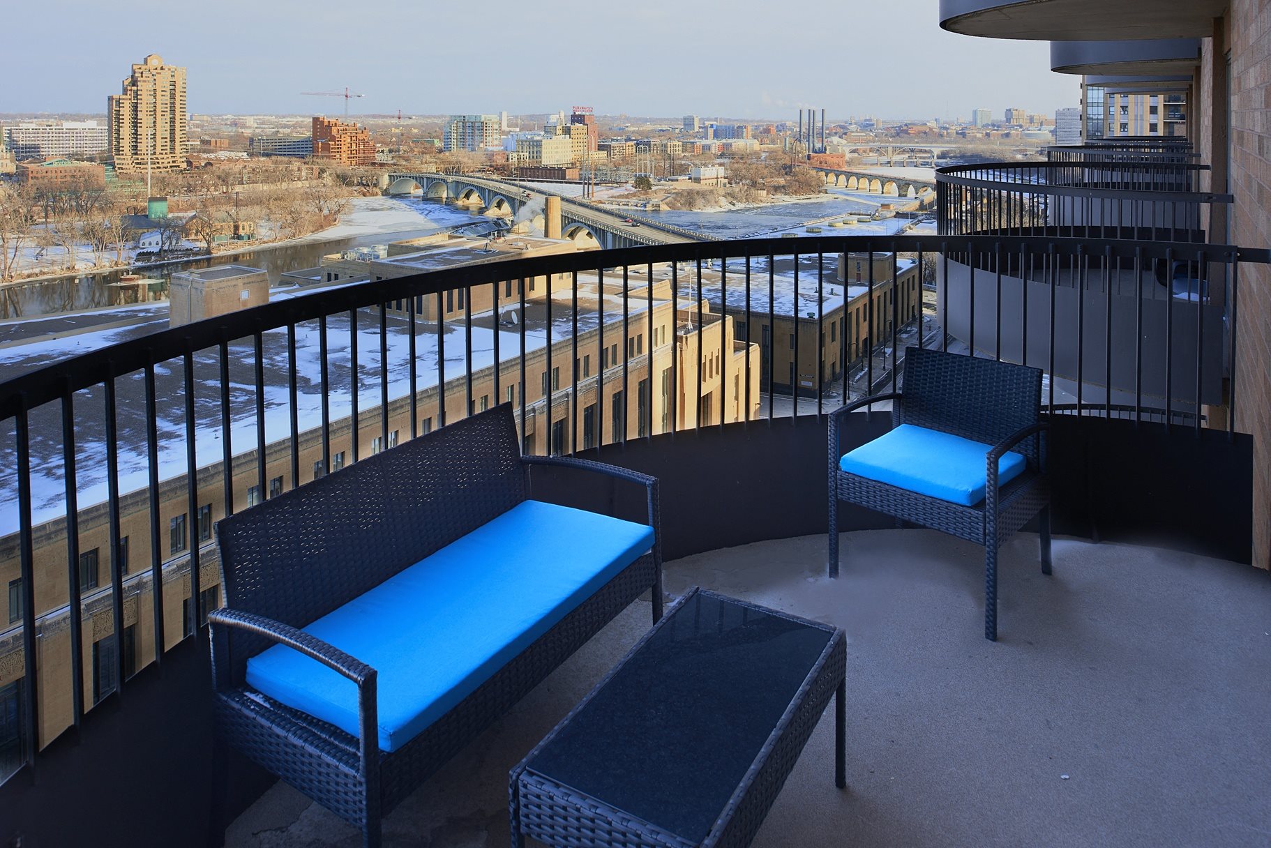 A balcony with a black railing has two chairs and a table.
